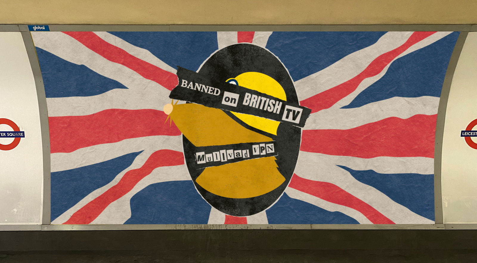 A Mullvad VPN advertisement displayed in the London Underground. The background features a weathered Union Jack flag. In the center, a black oval contains the Mullvad logo. Pieces of black tape with white, ransom-style text are layered over the logo, reading 'BANNED on BRITISH TV' and 'MULLVAD VPN'. The edges of the image show the 'Leicester Square' station signs.